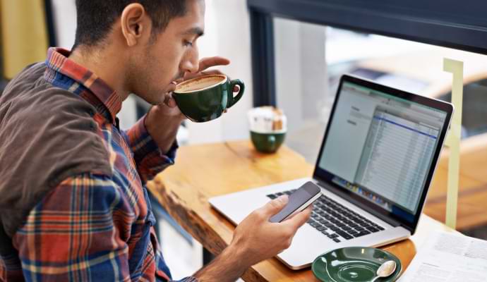 femeie pe canapea care se uită la telefonul mobil lansând Norton 360 cu AntiVirus Plus.